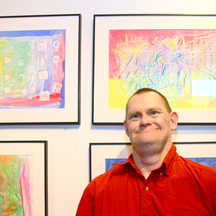 Tim wears a red shirt and smiles in an art gallery during CATA's 2016 Annual Art Show