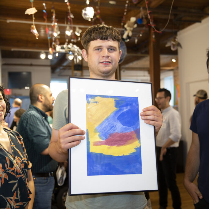 Rory holds his framed painting in an art gallery during CATA's 2019 Annual Art Show