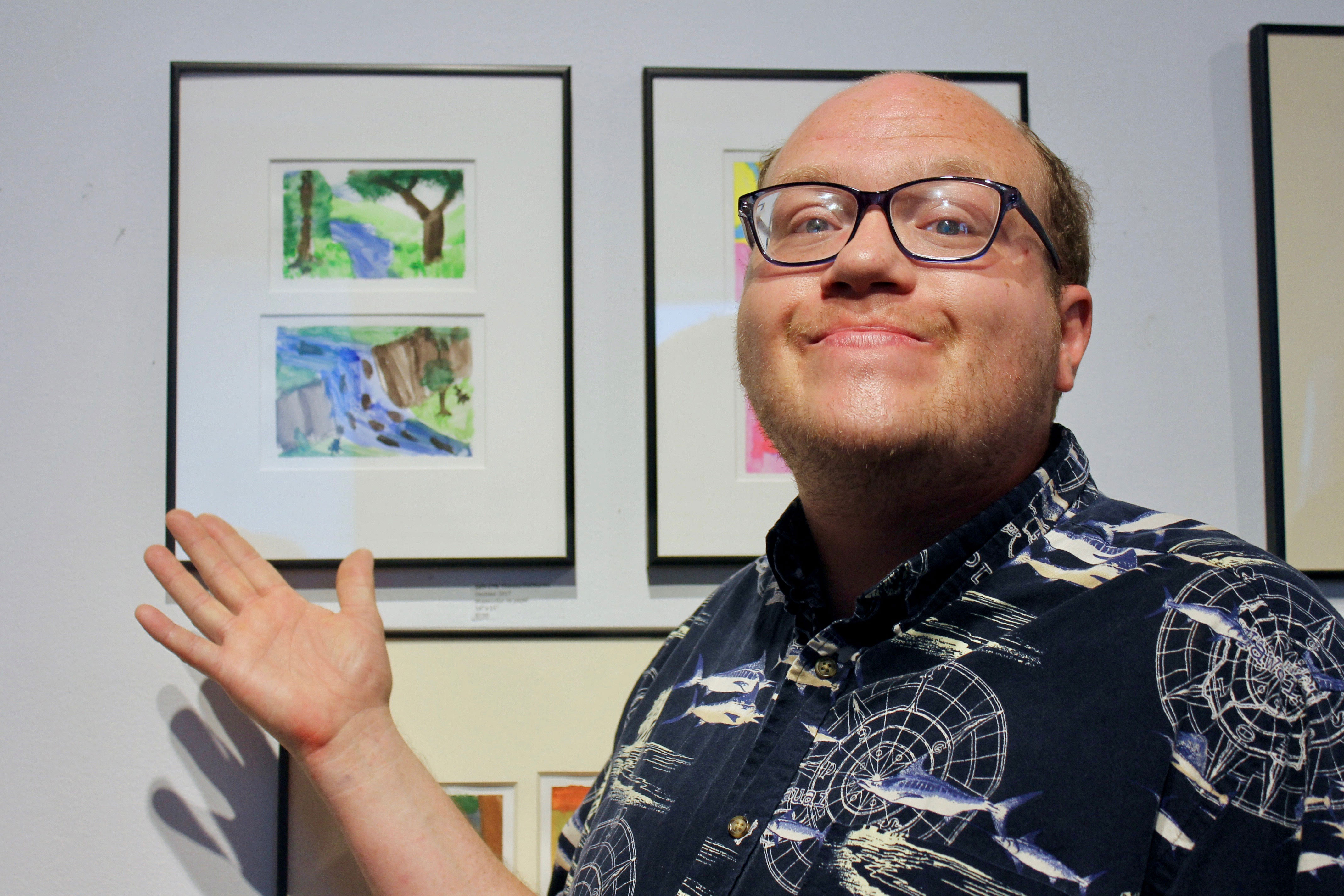 Tom smiles and points to his artwork in CATA's 2018 Annual Art Show