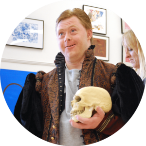 Photo of smiling CATA artist Dan wearing a Shakespearean costume and holding a skull