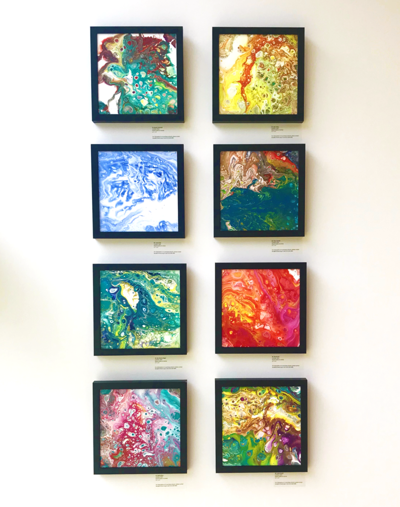 Eight square colorful paintings on a wall
