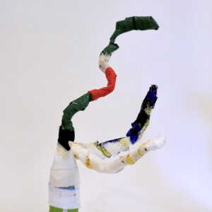 Mixed Media bottle sculpture with white fabric body, two arms- one white and one painted partially navy. Creature has a long neck painted alternating sections of green and orange.