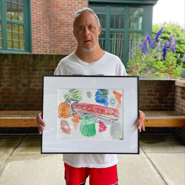 Dan stands outside holding his framed painting
