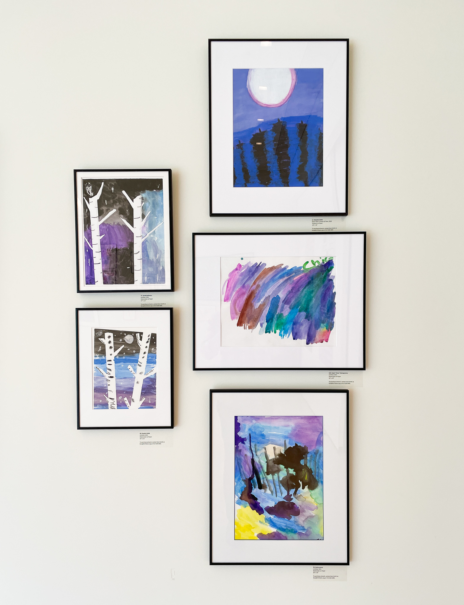 Gallery wall with five paintings in tones of blue and purple