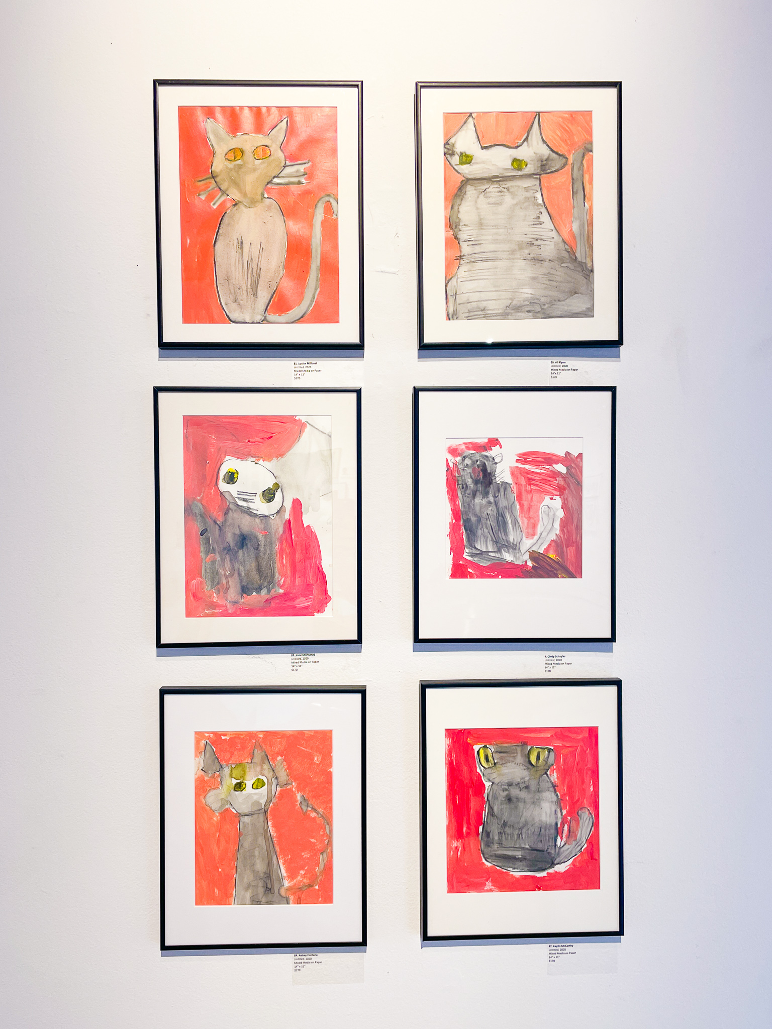 A gallery wall with six paintings of cats with orange backgrounds
