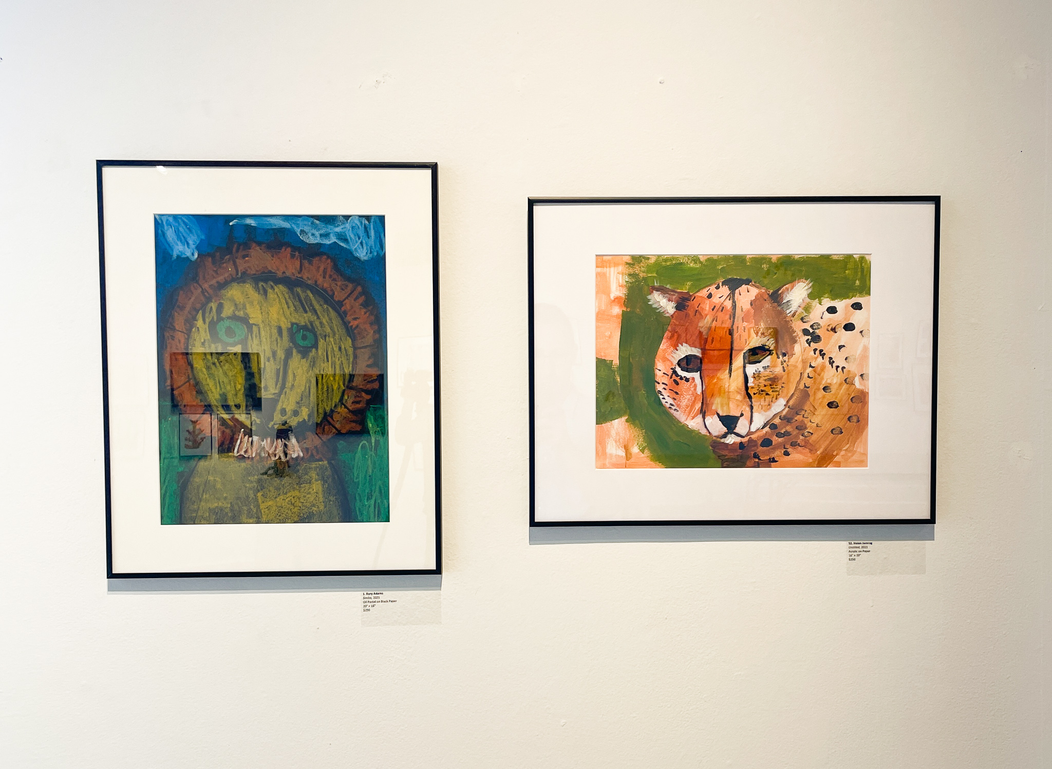 A gallery wall with two framed paintings, one of a lion on the left, the other of a cheetah on the right