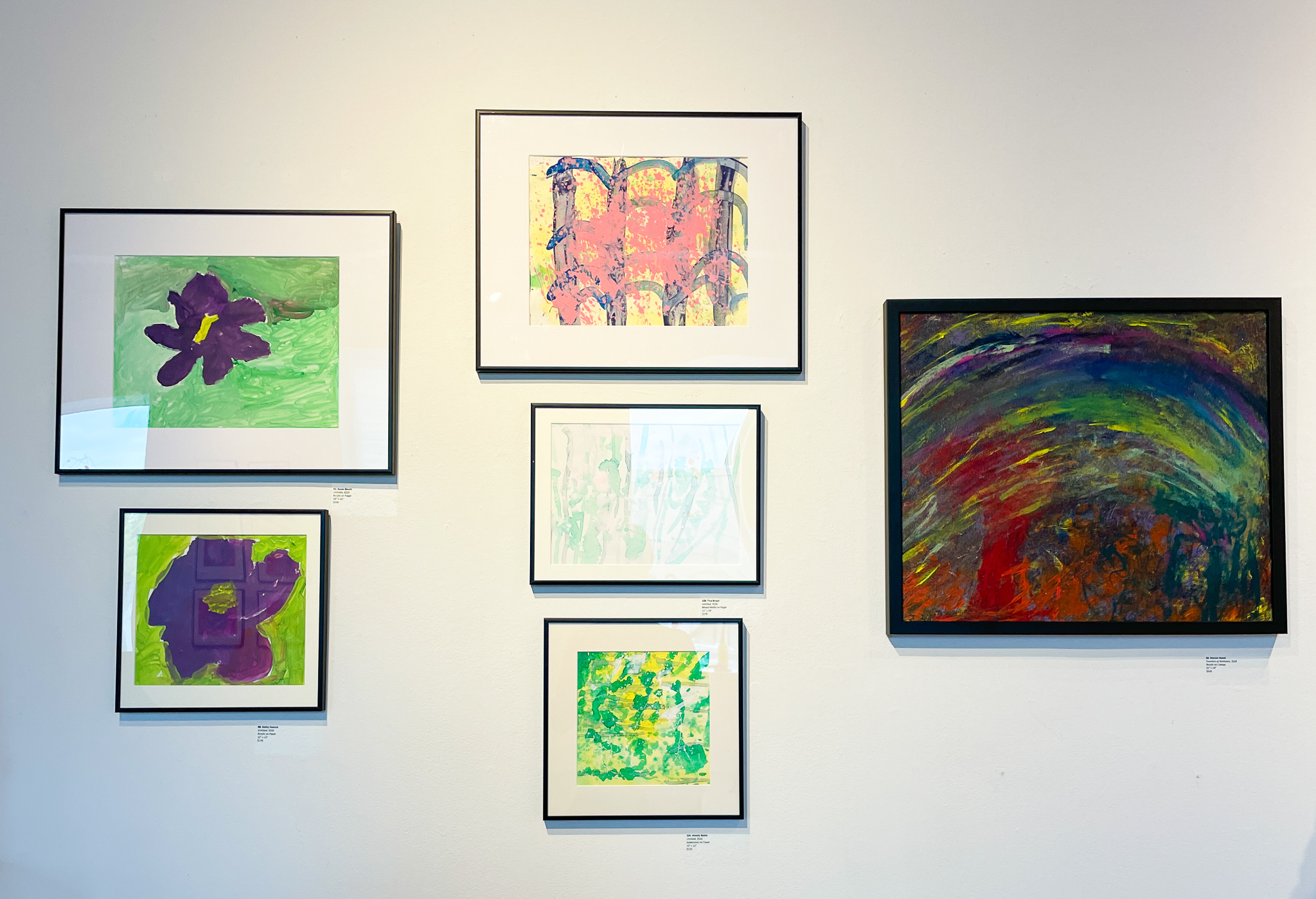 Gallery wall with six abstract paintings of various sizes and colors