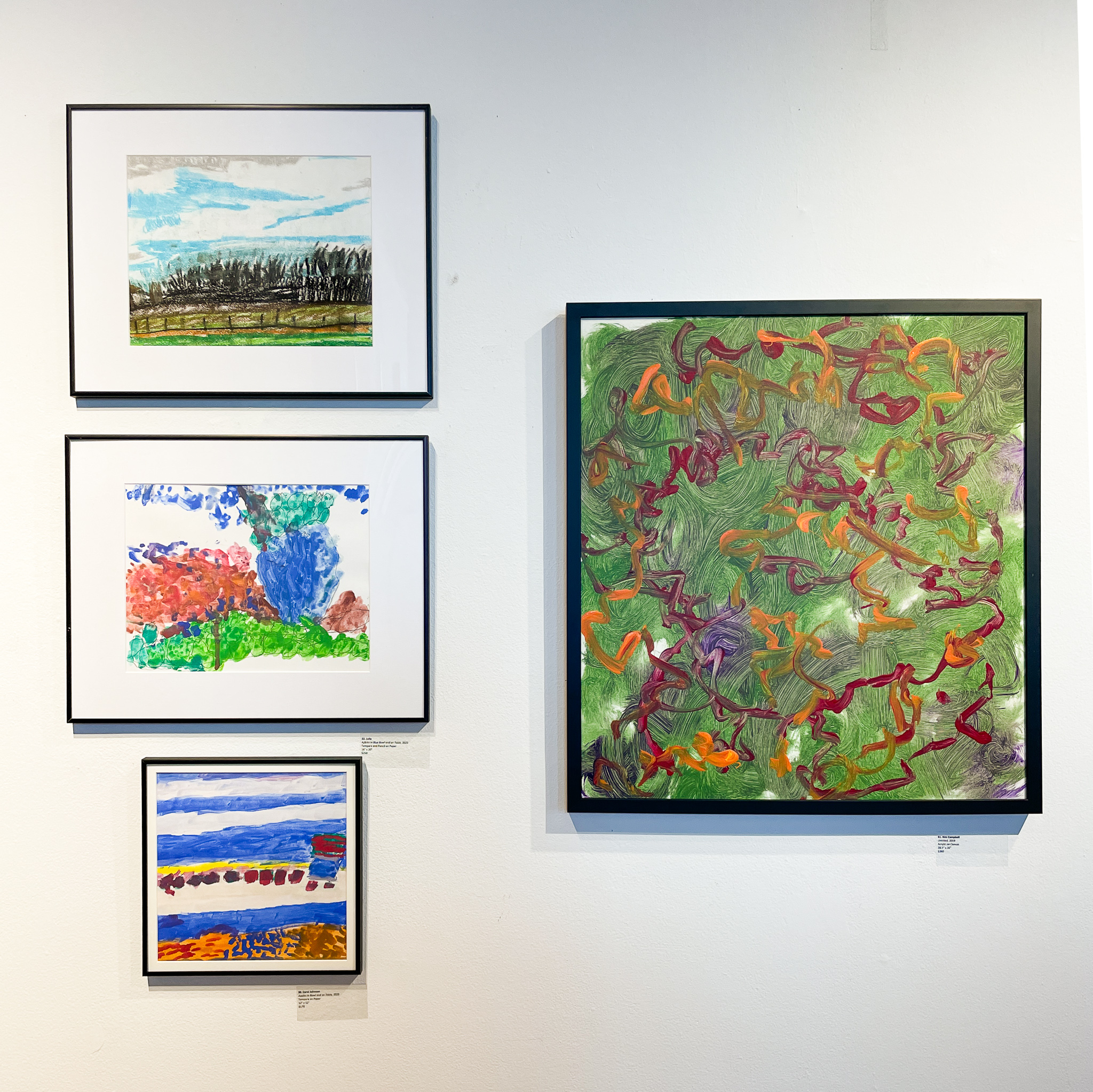 Gallery wall with four abstract paintings in tones of green, blue, and brown