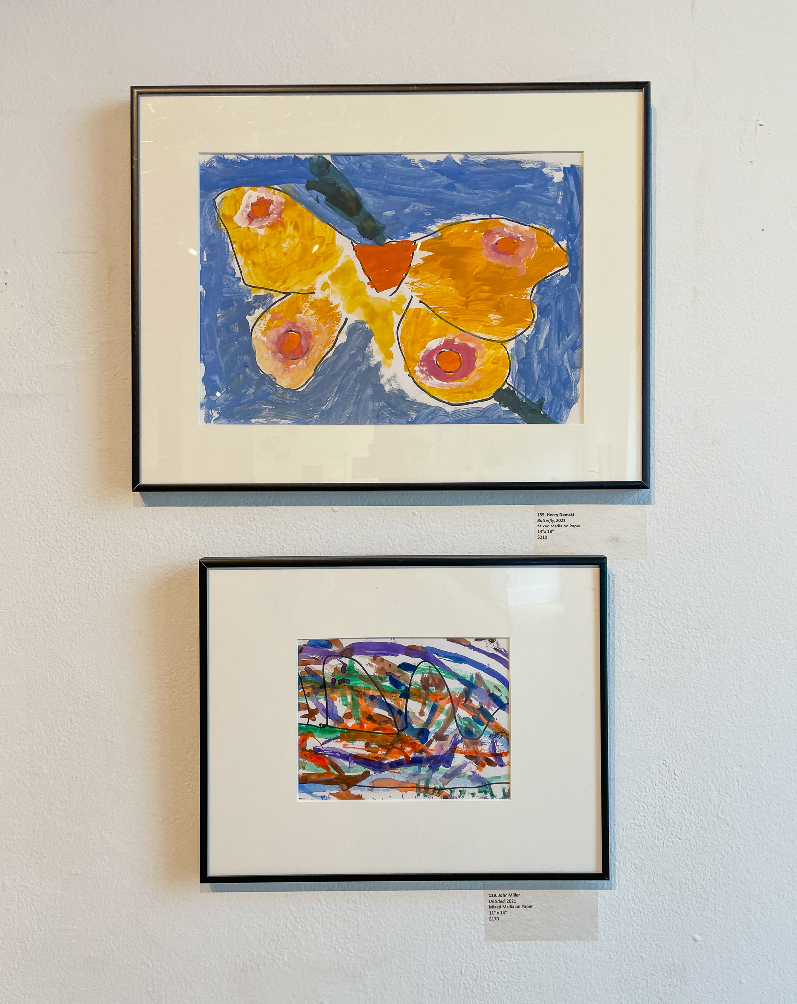 Gallery wall with two painting, one a large butterfly and the other an abstract painting
