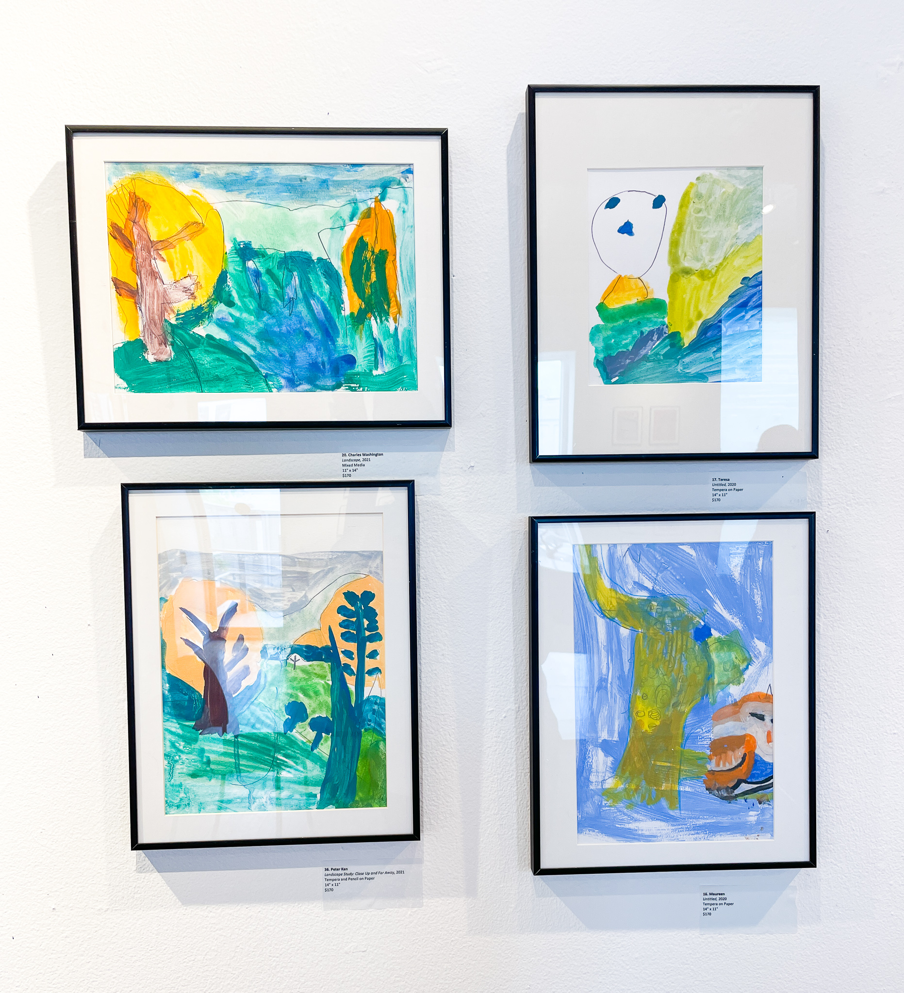 Gallery wall with four landscape paintings, each with blues and greens
