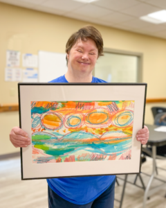 CATA artist Cathy smiles and holds her framed painting