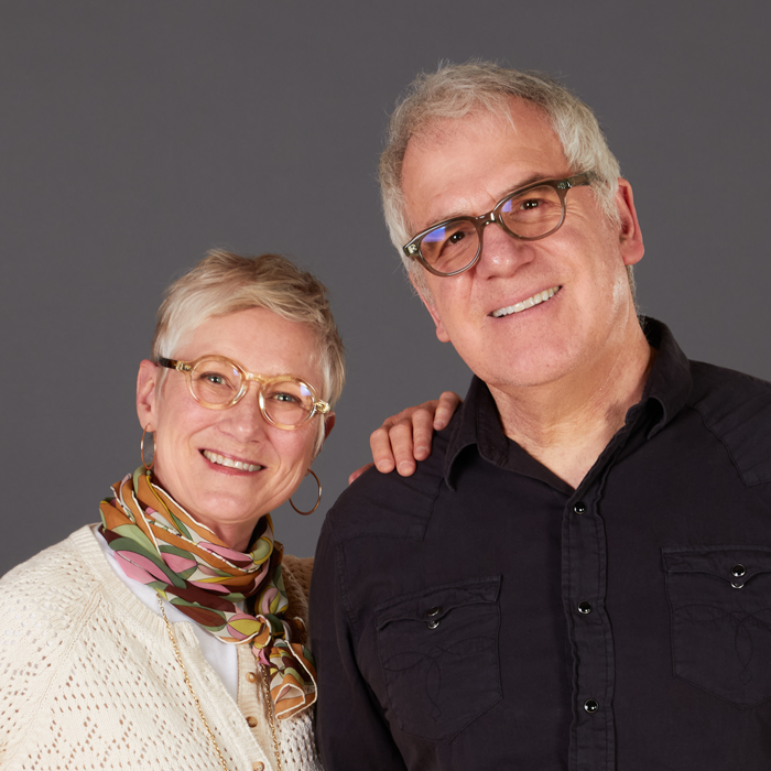 A headshot of Caitlin and Mitch Nash standing in front of a grey background.