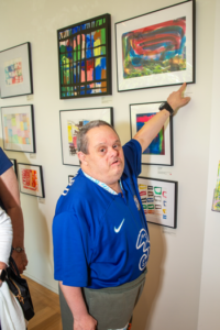 CATA artist Ed stands and points to his framed painting on the wall of the Clark Art Institute