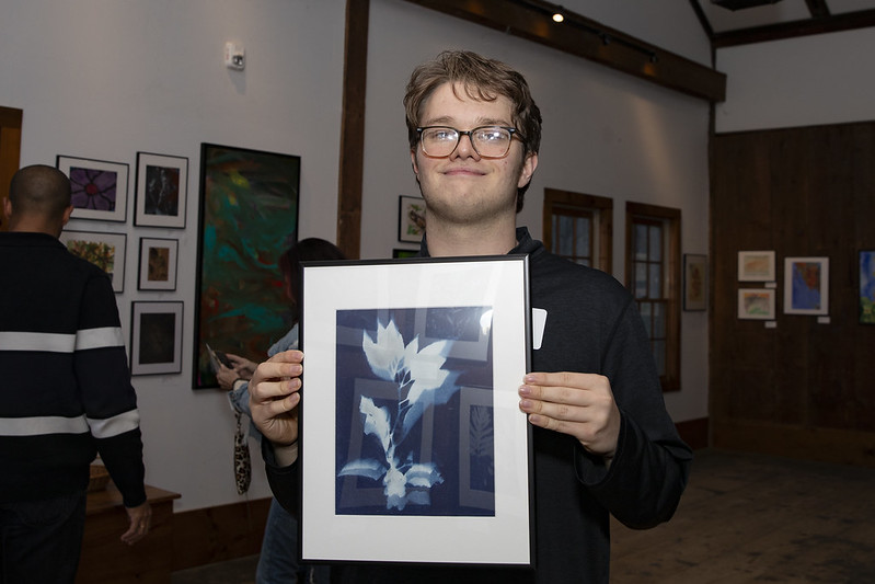 CATA artist Max holds his framed cyanotype print in CATA's exhibit at Pleasant Valley