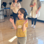 A young boy wears noise cancelling headphones and claps to music