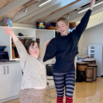 Sandra and Rockette dancer Katie Drablos hold their hands up and smile in a dance pose