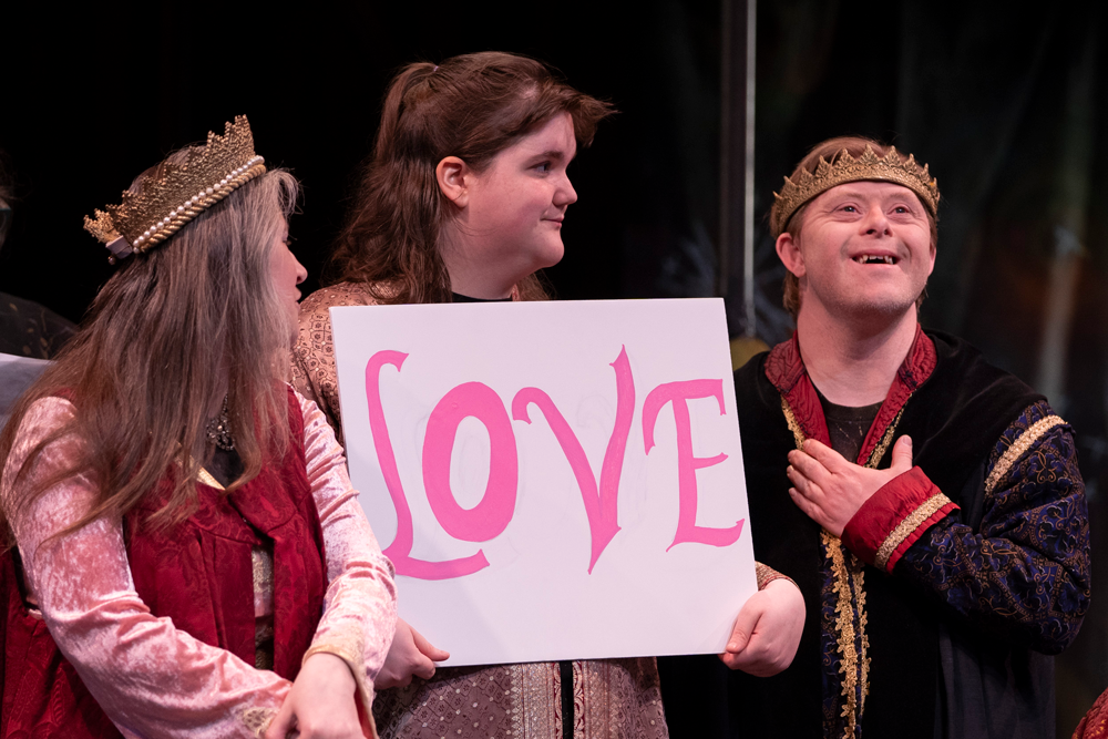 CATA artists perform in Shakespearean costumes holding a sign that says "LOVE" in CATA's Matinee performance