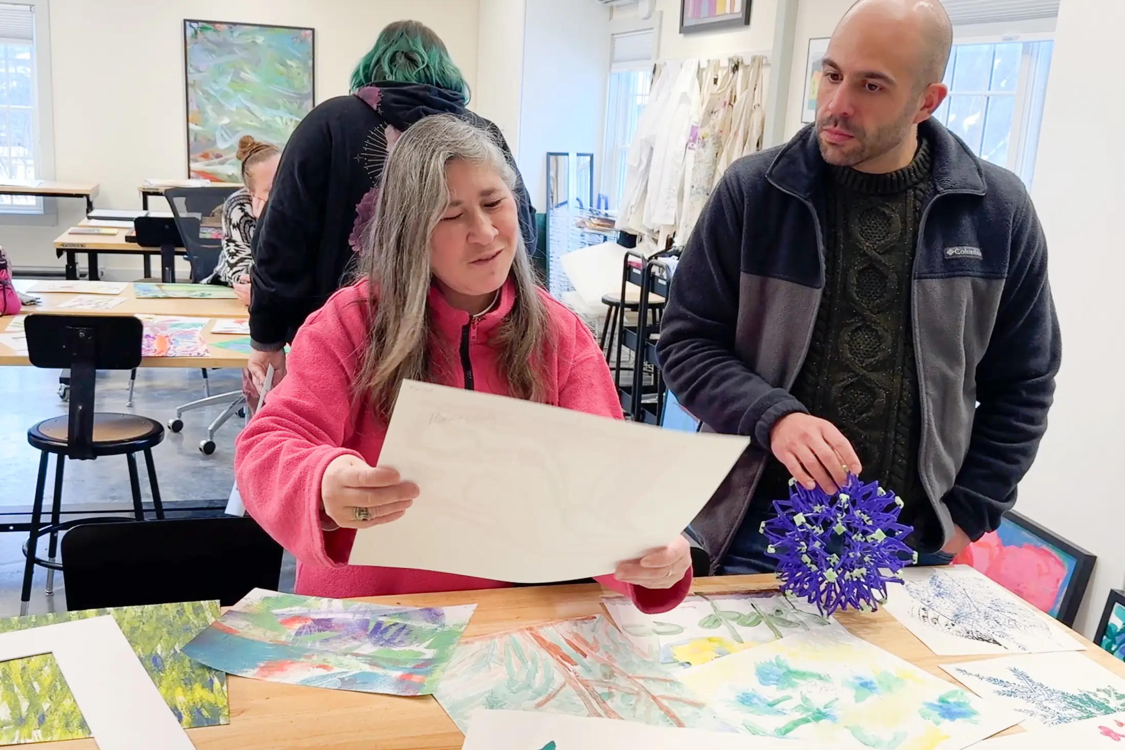 Two people examine a piece of art. 