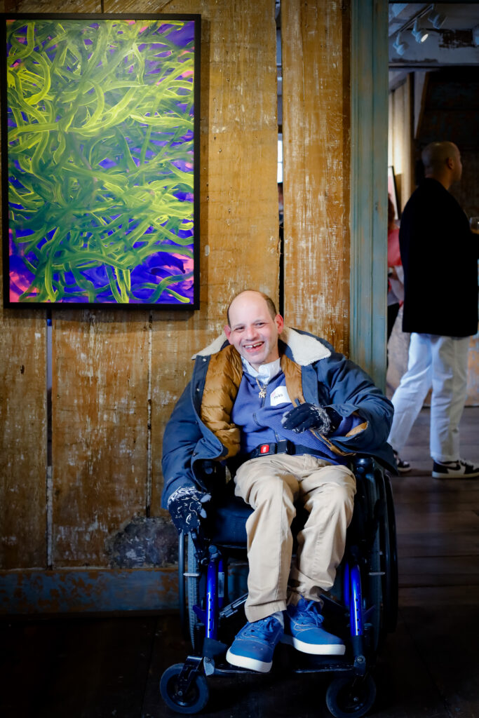 Photo: Artist Myles Tosk (BCArc Center for Development) with his painting “Full of Daisies”