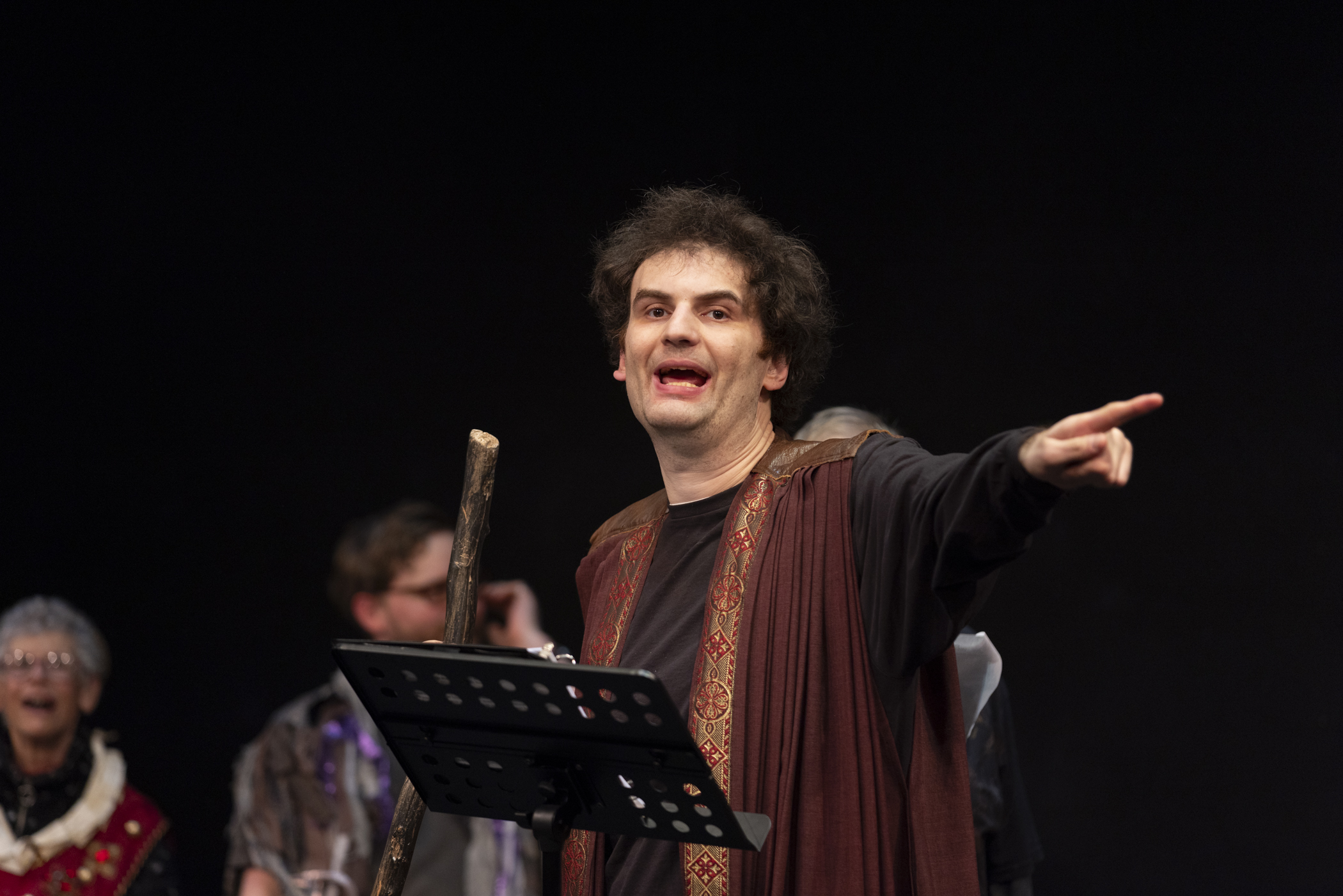 Ethan points into the audience, commanding the stage as Prospero.