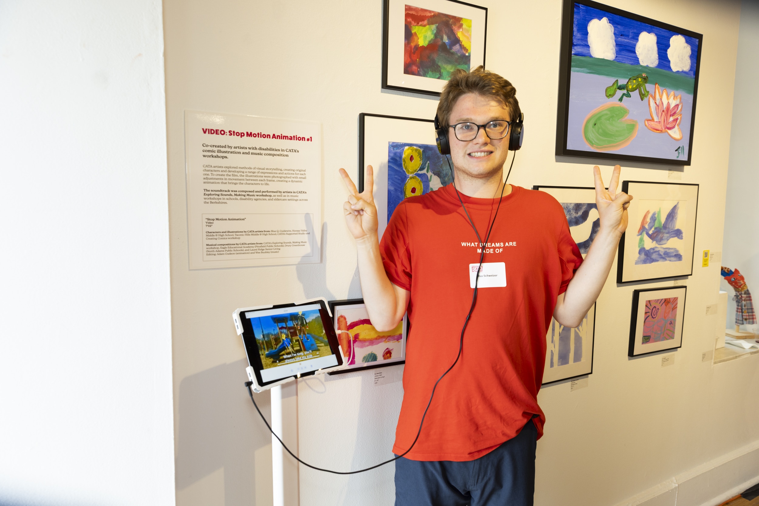 A CATA artist wears headphones and poses next to a screen showing an animation.