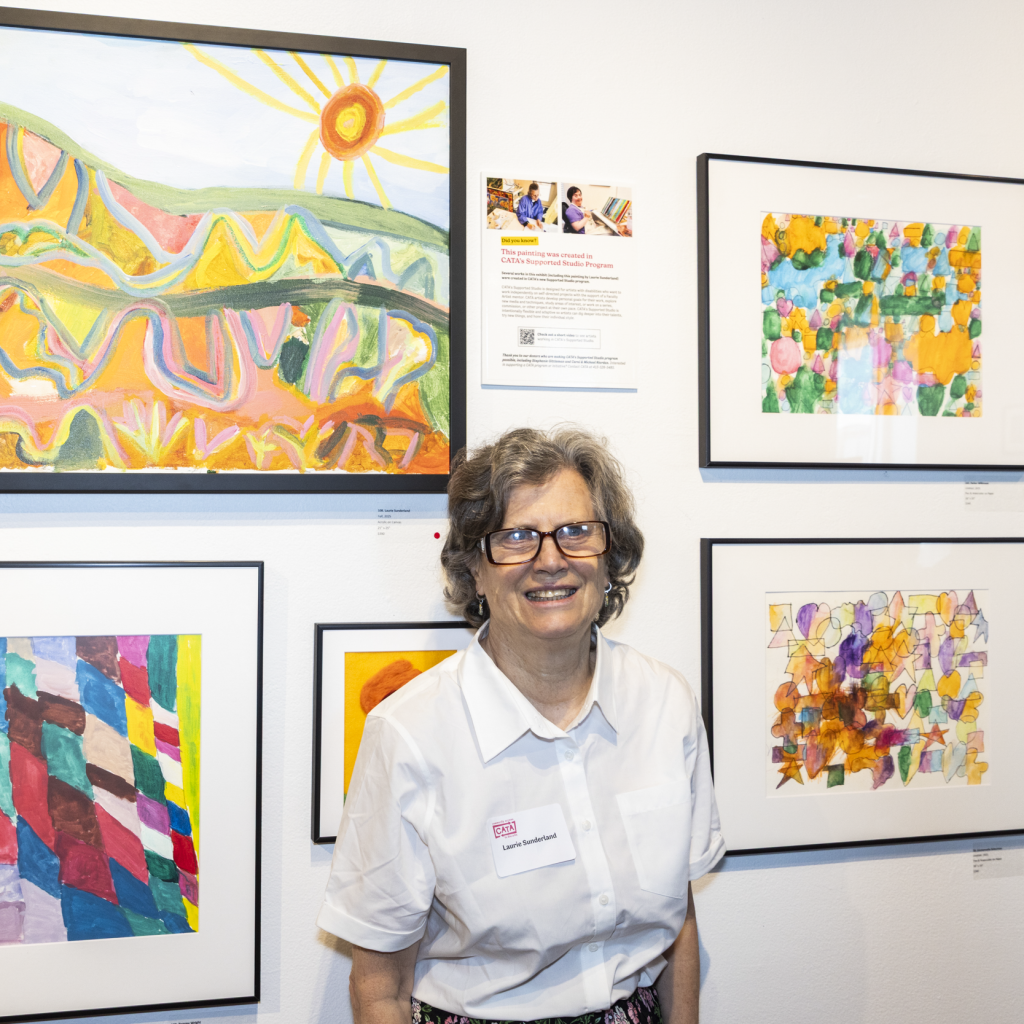 A CATA artist stands with a landscape painting.