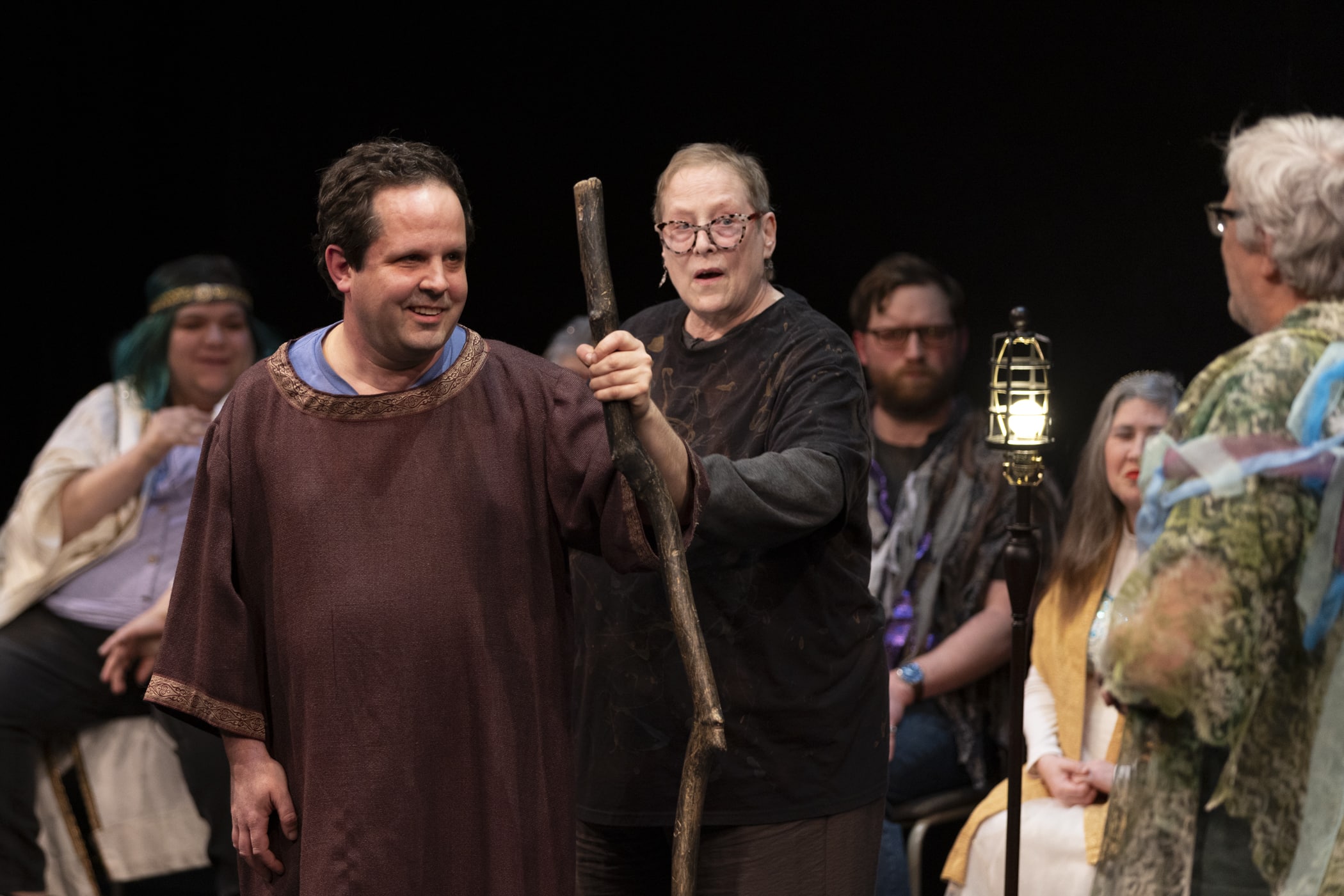 A man in costume with a staff smiles onstage.