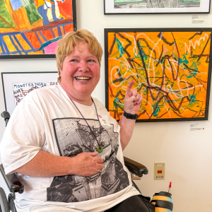 A woman pointing to a vibrant orange painting.