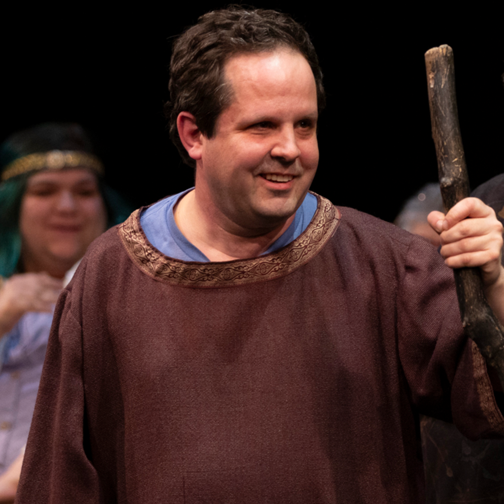 A man holding a staff onstage.