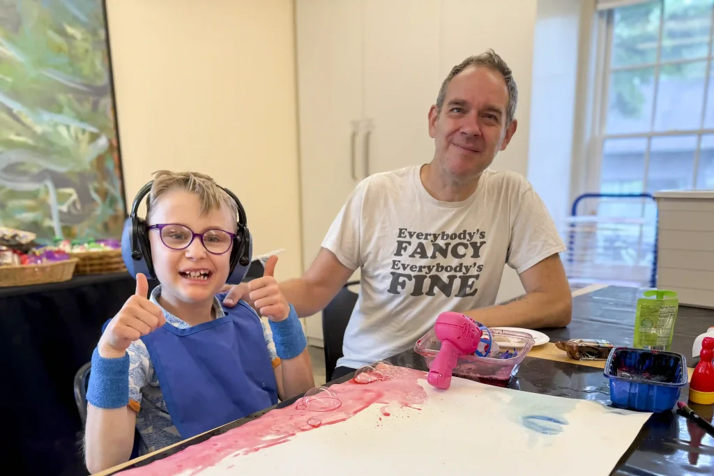 A young boy and his father make art together.